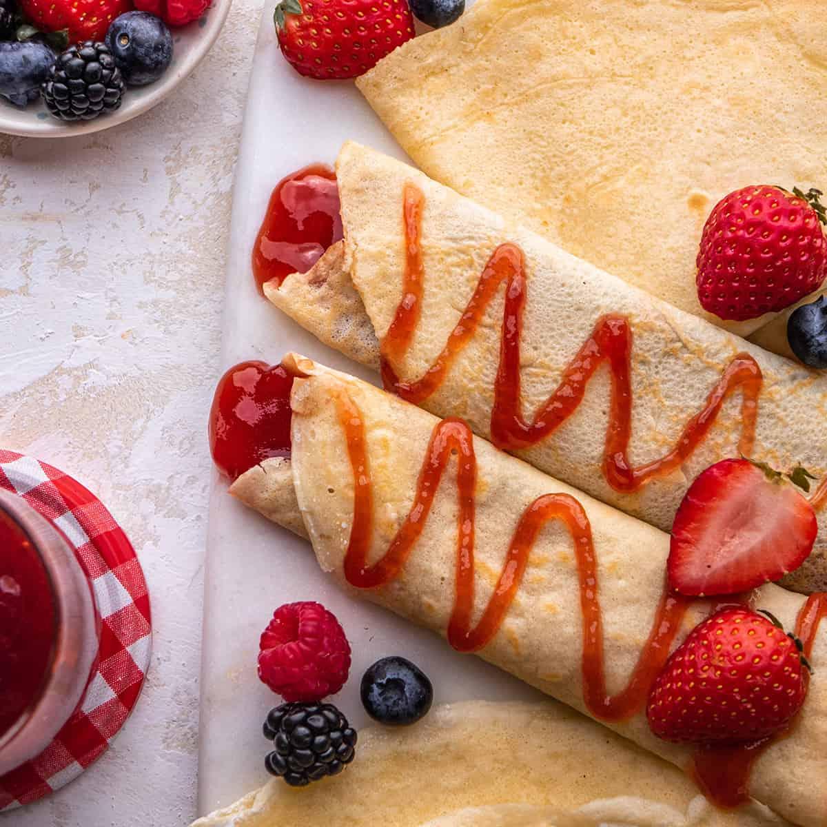 δύο κρέπες γεμισμένες και περιχυμένες με μαρμελάδα φράουλας