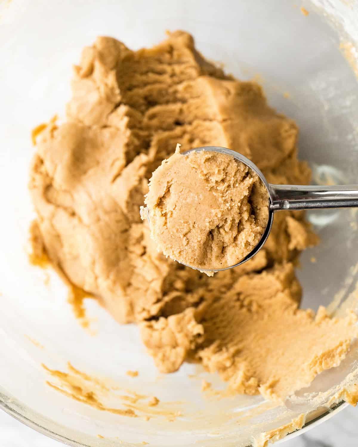 φτιάχνοντας συνταγή Peanut Butter Blossoms σε μίξερ - ένα κουτάλι μπισκότων που μετράει τη κρυωμένη ζύμη