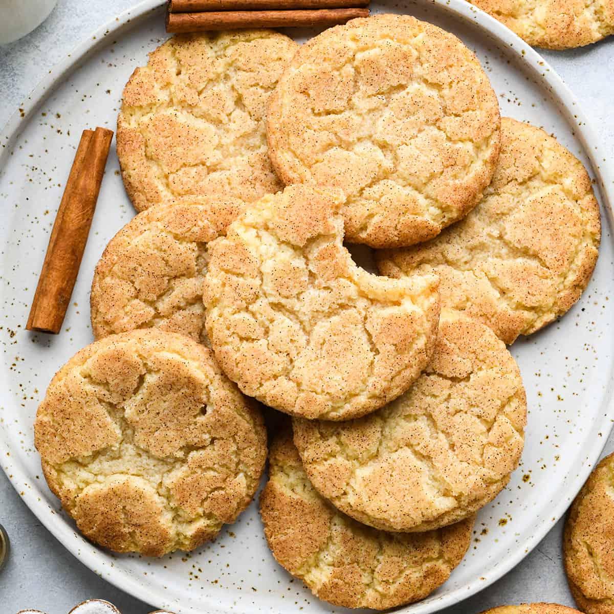 Η ΚΑΛΥΤΕΡΗ συνταγή για Snickerdoodle ποτέ! Αυτά τα μπισκότα snickerdoodle έχουν τραγανές άκρες, μαστιχωτό κέντρο και πλούσια γεύση κανέλας. Είναι εύκολο να φτιαχτούν χωρίς ψύξη ή περίεργα υλικά! Μια κλασική χριστουγεννιάτικη συνταγή που πέρασε από τη γιαγιά μου και ψήνω από τότε που ήμουν μικρό κορίτσι!#snickerdoodle #snickerdoodles #snickerdoodlecookies #christmascookies #bestsnickerdoodlerecipe #recipe #cookies 8 μπισκότα snickerdoodle σε πιάτο, ένα έχει φαγωθεί ένα κομμάτι