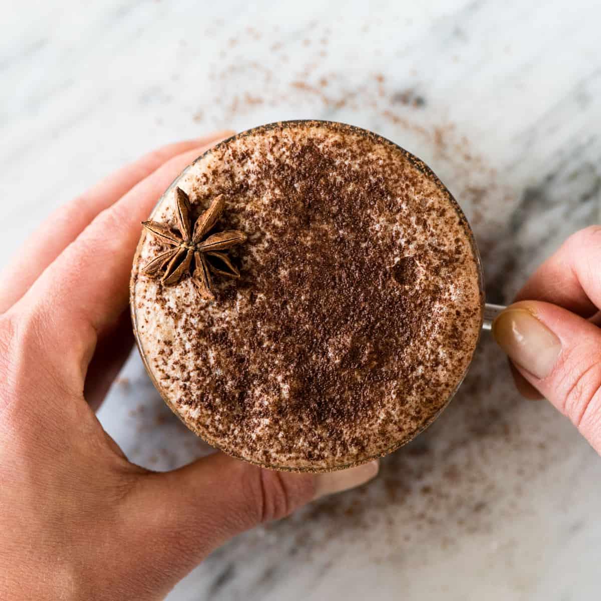 Πάνω όψη χεριών που κρατούν μια κούπα Vegan Mocha Latte χωρίς γαλακτοκομικά