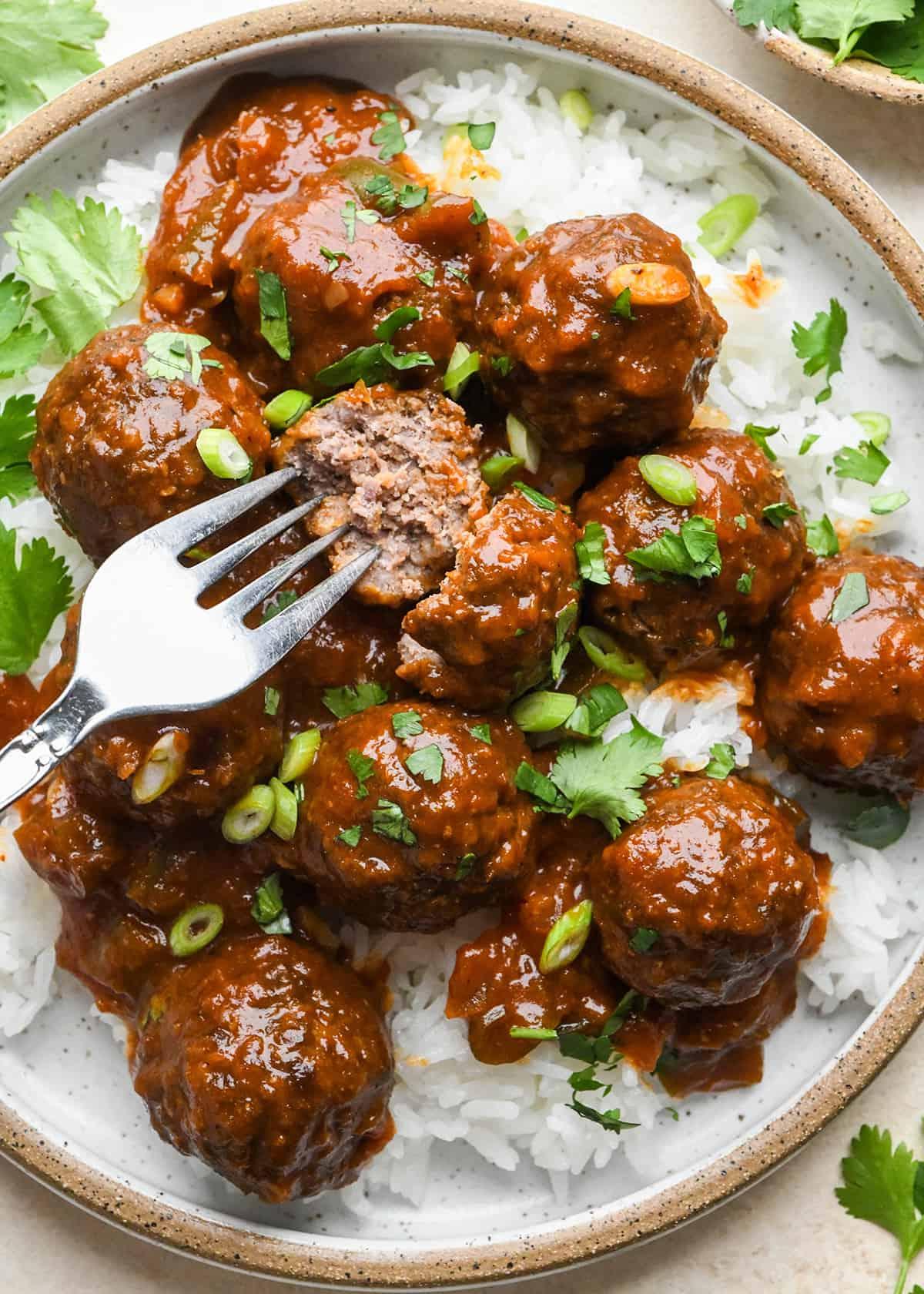 Κεφτέδες Μπάρμπεκιου 6 Κεφτεδάκια BBQ σε πιάτο πάνω από ρύζι, ένα κομμένο στη μέση με ένα πιρούνι.
