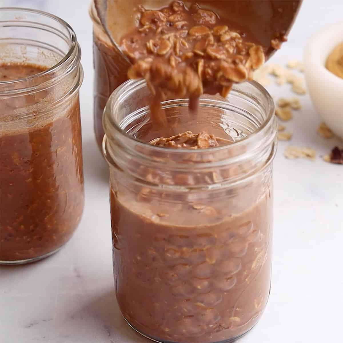 Chocolate Peanut Butter Overnight Oats being poured into glass jars