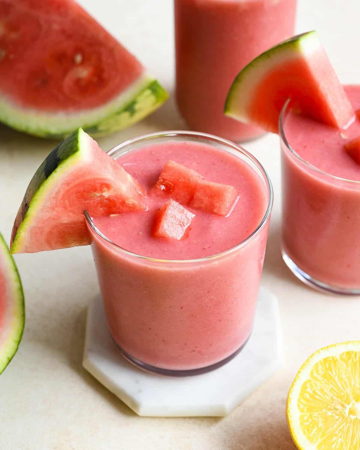 Δύο ποτήρια smoothie καρπούζι με κομμάτια και φέτες καρπουζιού