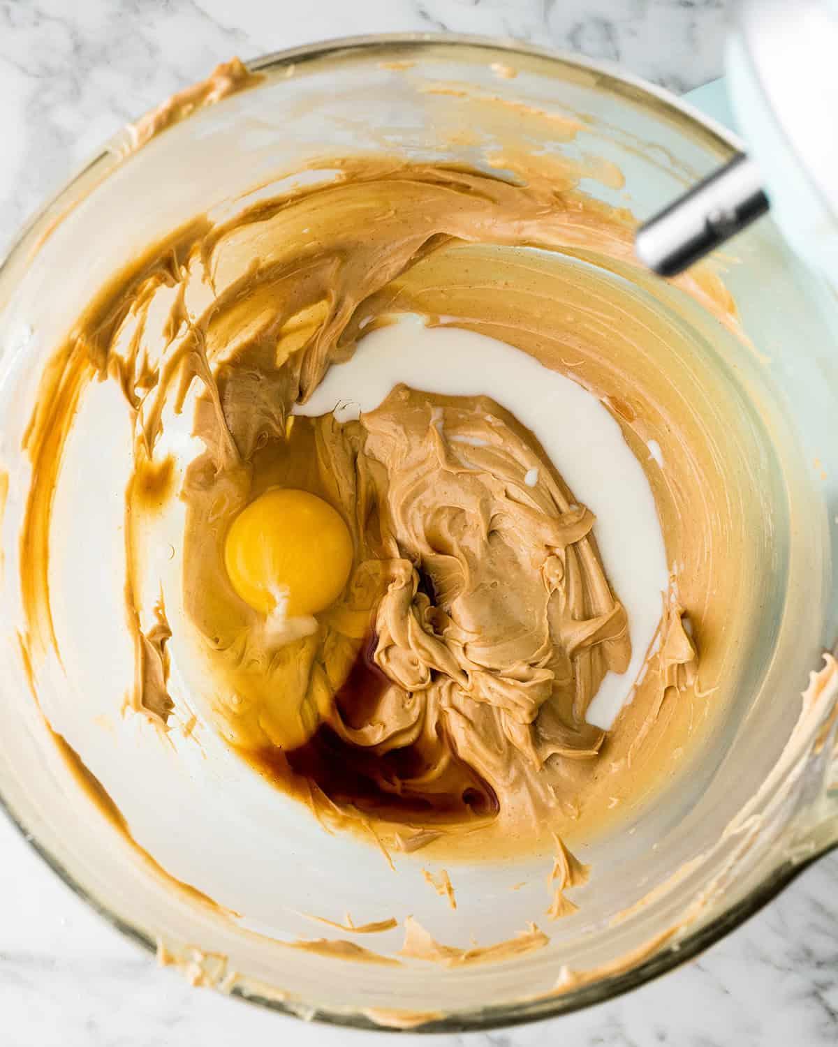 φτιάχνοντας συνταγή Peanut Butter Blossoms σε μίξερ - προσθήκη αυγού, βανίλιας και γάλακτος