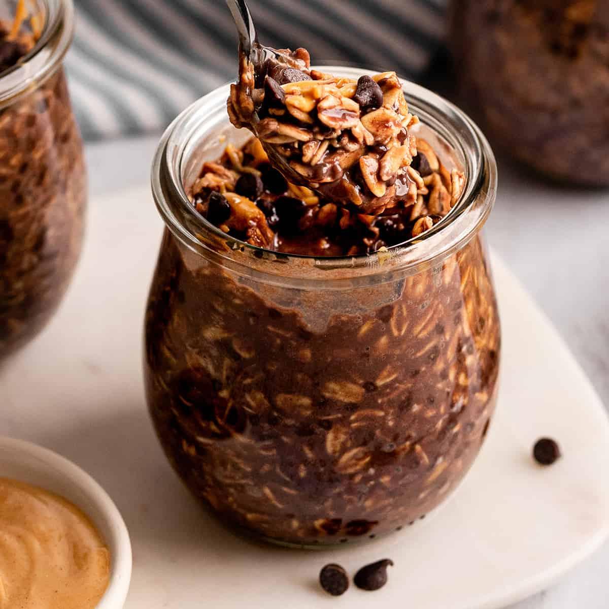a spoon taking a scoop of Chocolate Peanut Butter Overnight Oats out of a jar