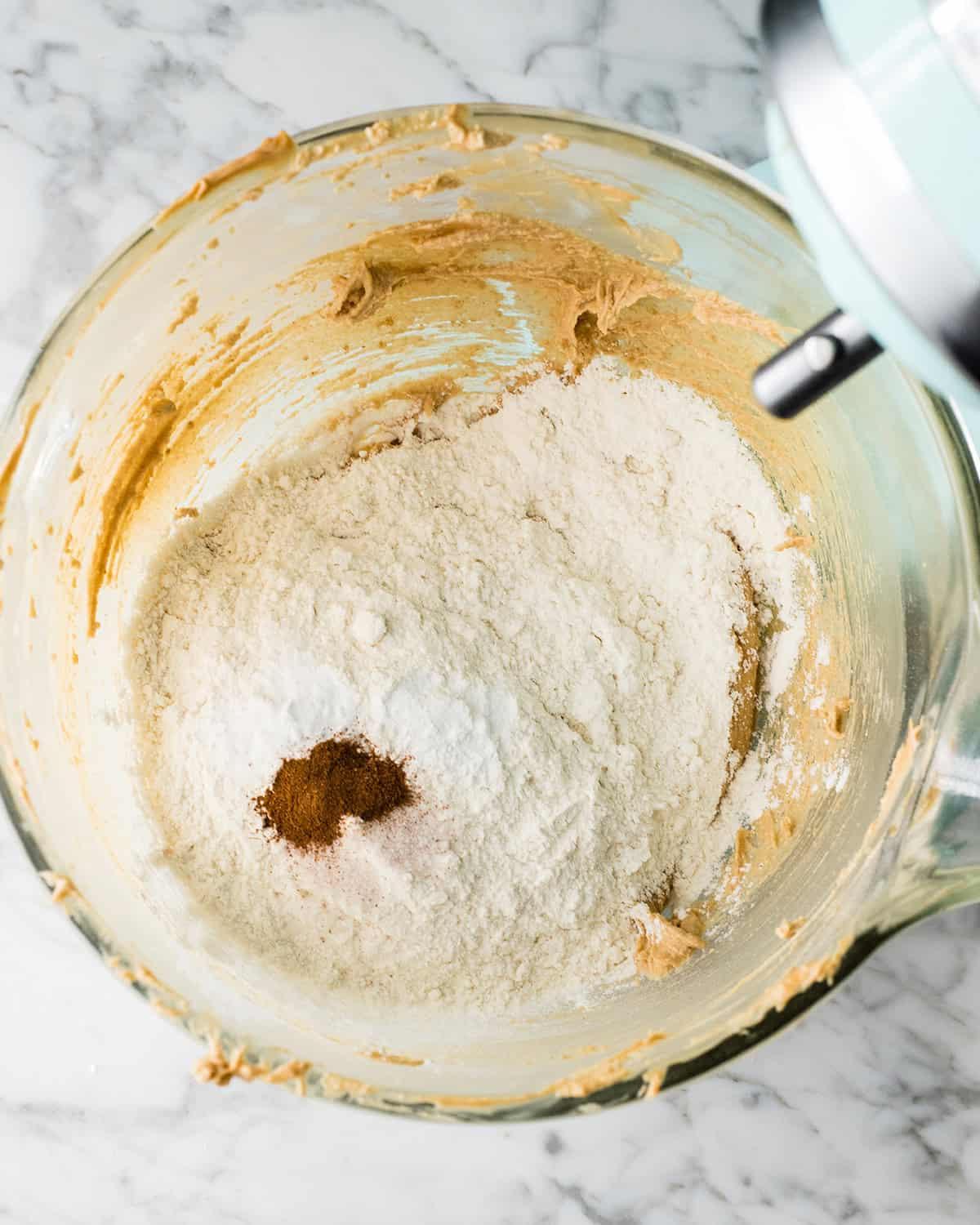 φτιάχνοντας συνταγή Peanut Butter Blossoms σε μίξερ - προσθήκη στεγνών υλικών πάνω από τα υγρά υλικά