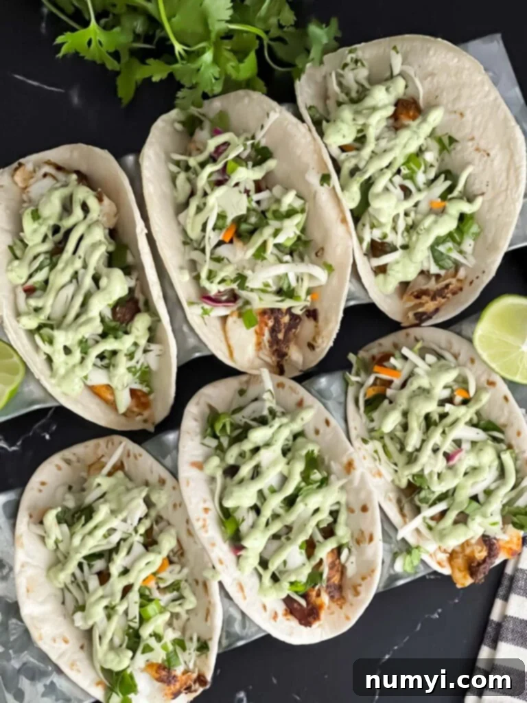 Two beautifully assembled blackened fish tacos on a dark background, showcasing all the fresh toppings.