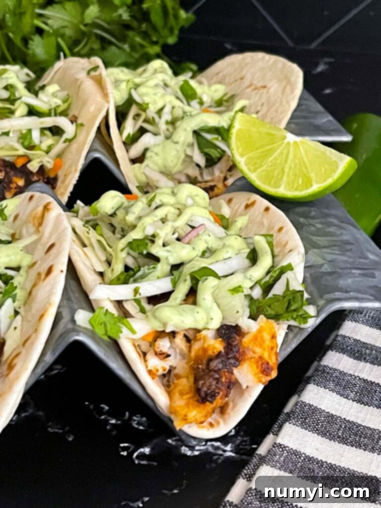 A close-up of a blackened fish taco, perfectly showcasing the flaky fish, slaw, and creamy sauce.