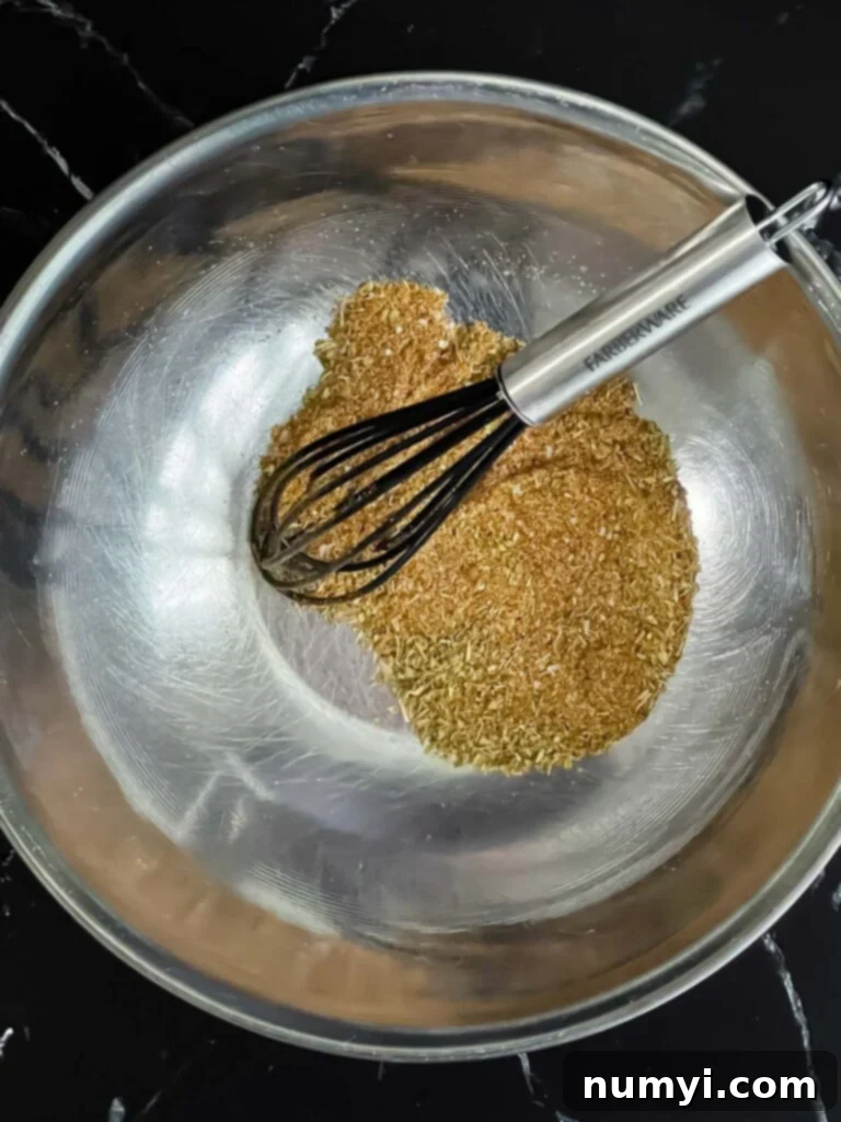 A bowl filled with a dark, smoky blackening spice mix for fish.