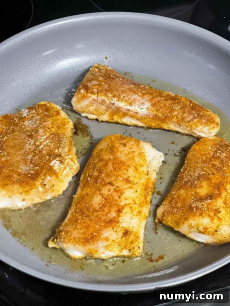 Blackened fish fillets sizzling in a hot cast iron skillet.