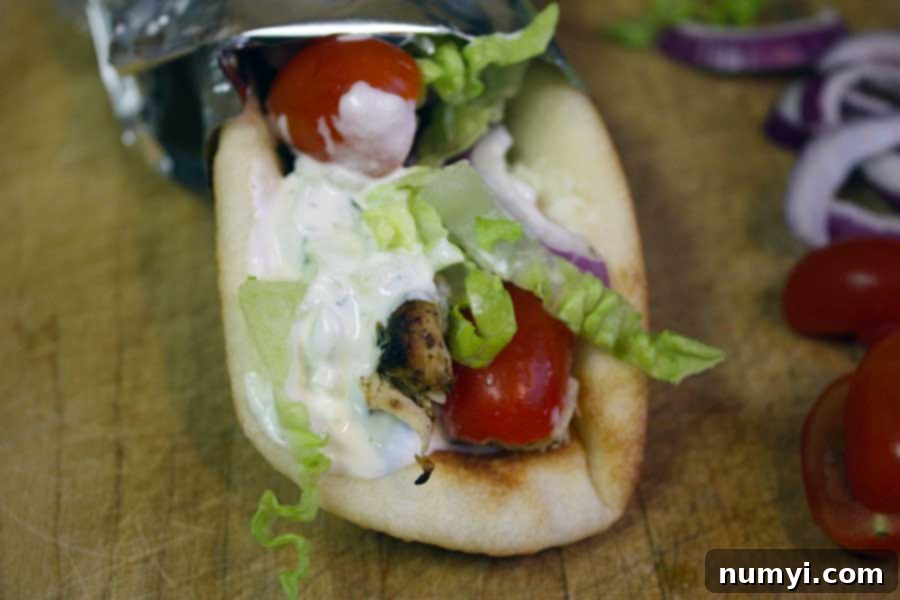 Chicken gyro wrapped in foil on a wooden board.