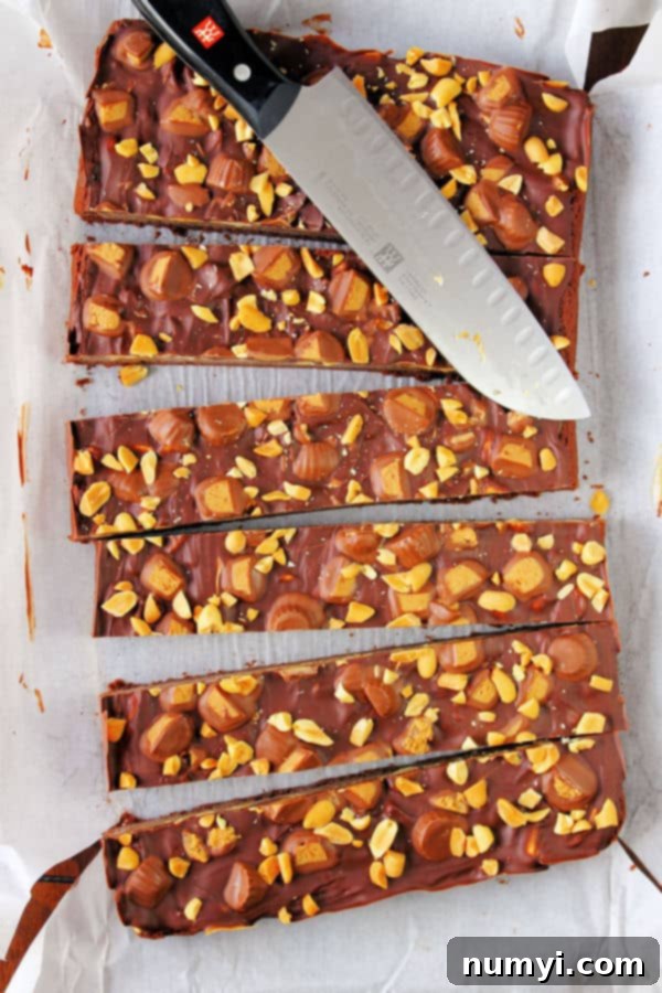 Peanut Butter Caramel Brownies cut into thin slices in the baking pan, showing off their distinct layers of chocolate, caramel, and peanut butter topping