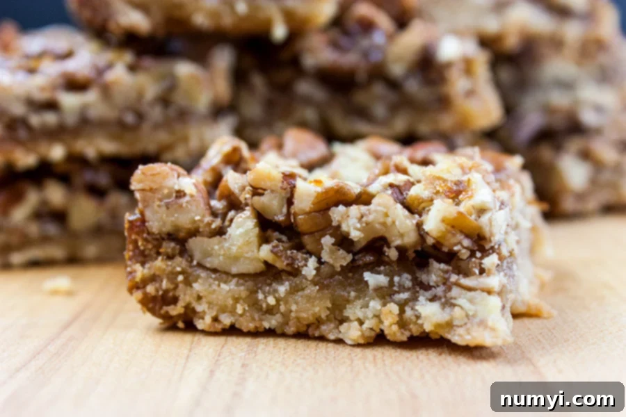 Golden Honey Pecan Pie Bars: Simply Sweet, No Corn Syrup Needed 3 Close-up of a stack of golden pecan pie bars with a crunchy pecan topping and a soft shortbread base.