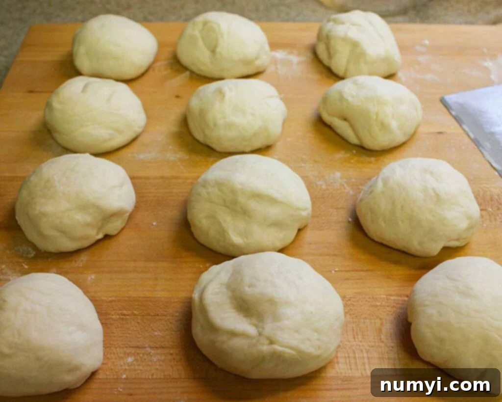 Naan dough balls formed on a wooden board.