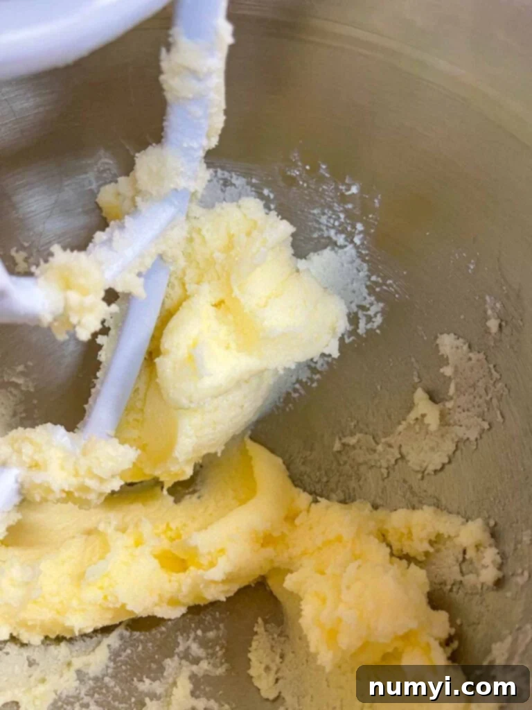 Spiced Eggnog Bundt with Creamy Glaze 3 Close-up of butter and granulated sugar being creamed together in a metal stand mixer bowl, showing a light and fluffy texture.