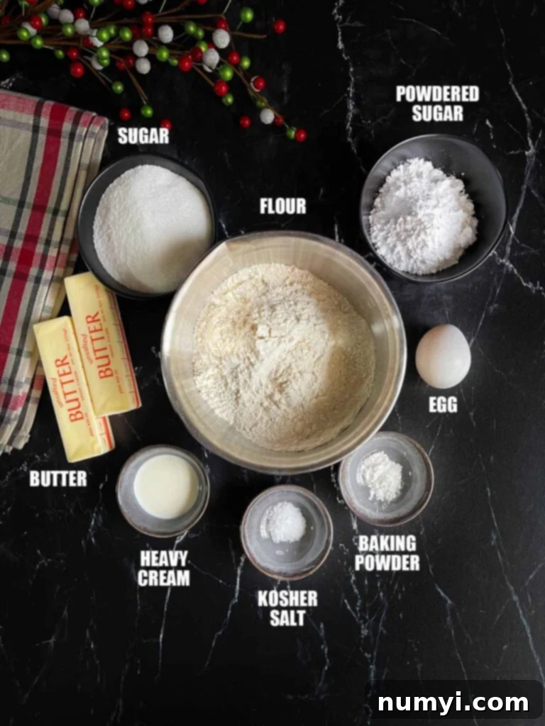 Various ingredients for cut out sugar cookie recipe, including flour, butter, sugar, and eggs, neatly arranged on a dark background.