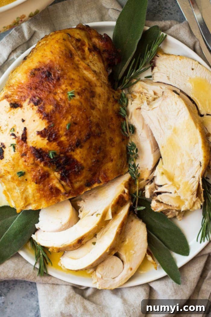 Golden brown turkey breast sliced on a white platter and generously drizzled with rich, homemade gravy, garnished with fresh herbs.