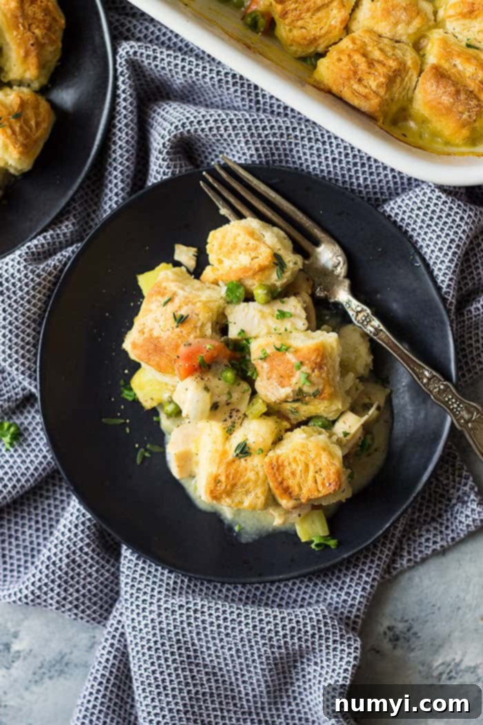 Homestyle Chicken & Biscuit Pot Pie 3 Serving of chicken pot pie with biscuits on a white plate with a fork.