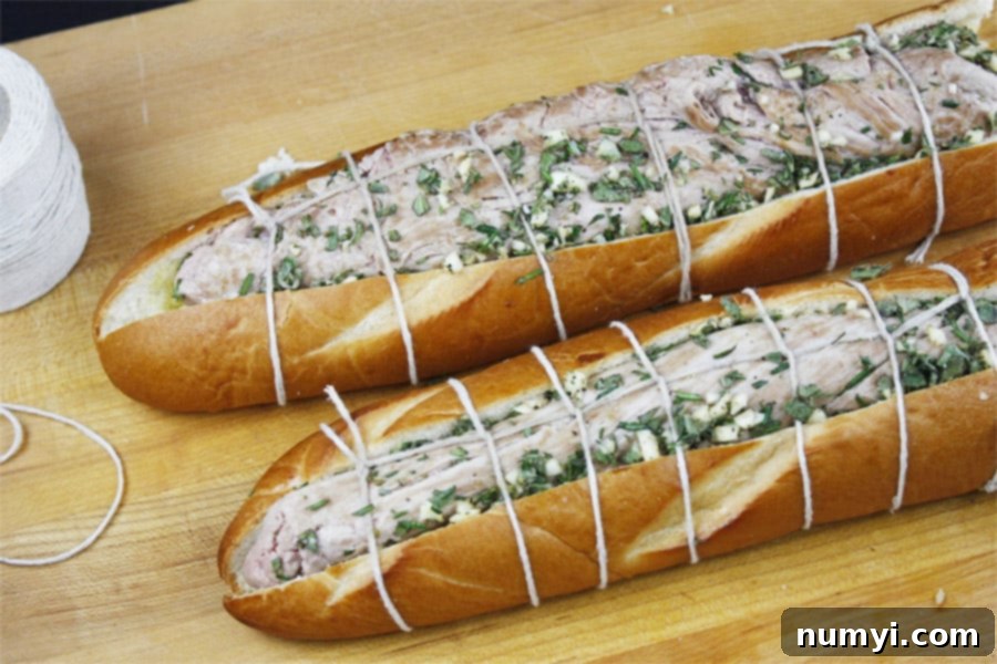 Herb-rubbed pork tenderloin nestled inside a hollowed-out baguette, tied with kitchen twine.