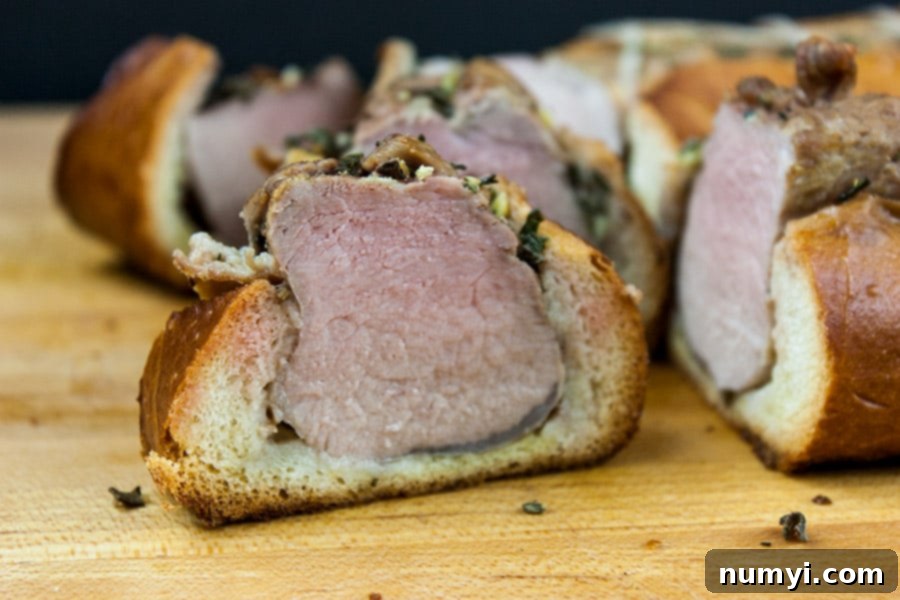 Sliced Tuscan pork tenderloin medallions in a baguette on a wooden cutting board.