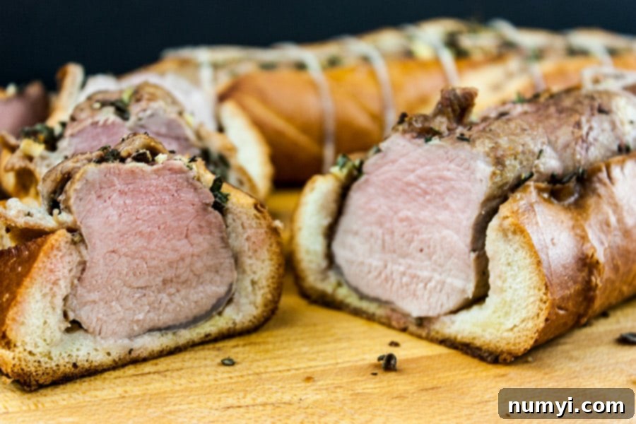Close-up of freshly sliced Tuscan pork tenderloin and baguette on a wooden cutting board.
