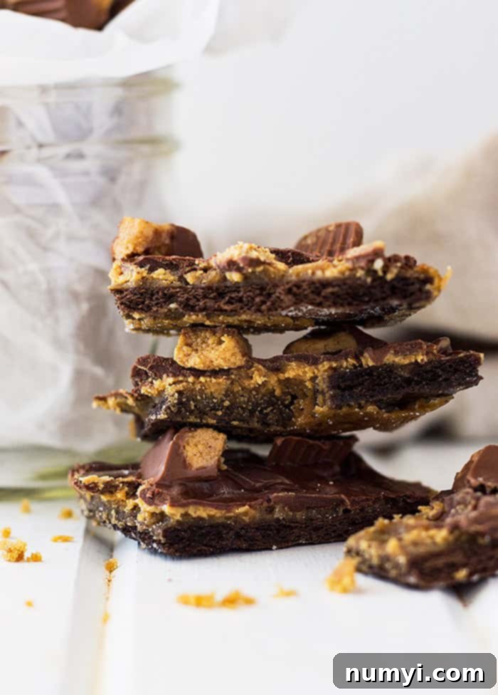 Close-up of a large batch of Peanut Butter Cup Graham Cracker Toffee cooling on parchment paper, showing the rich brown toffee, melted peanut butter, chocolate, and scattered chopped peanut butter cups. Ready to be broken into pieces.