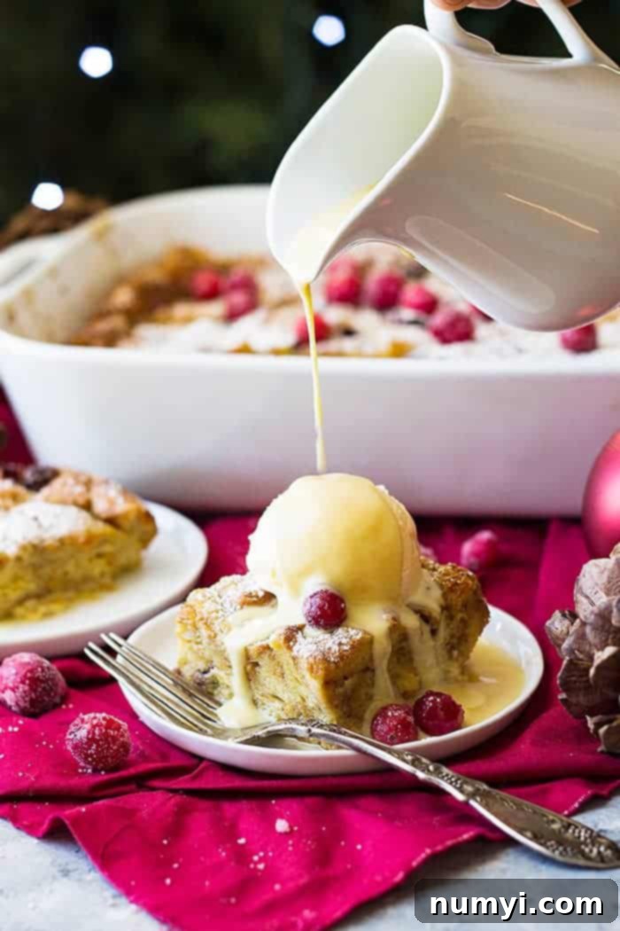 Close-up of a luxurious whiskey cream sauce being generously poured over a warm slice of cranberry bread pudding, highlighting its rich texture and decadent appeal.
