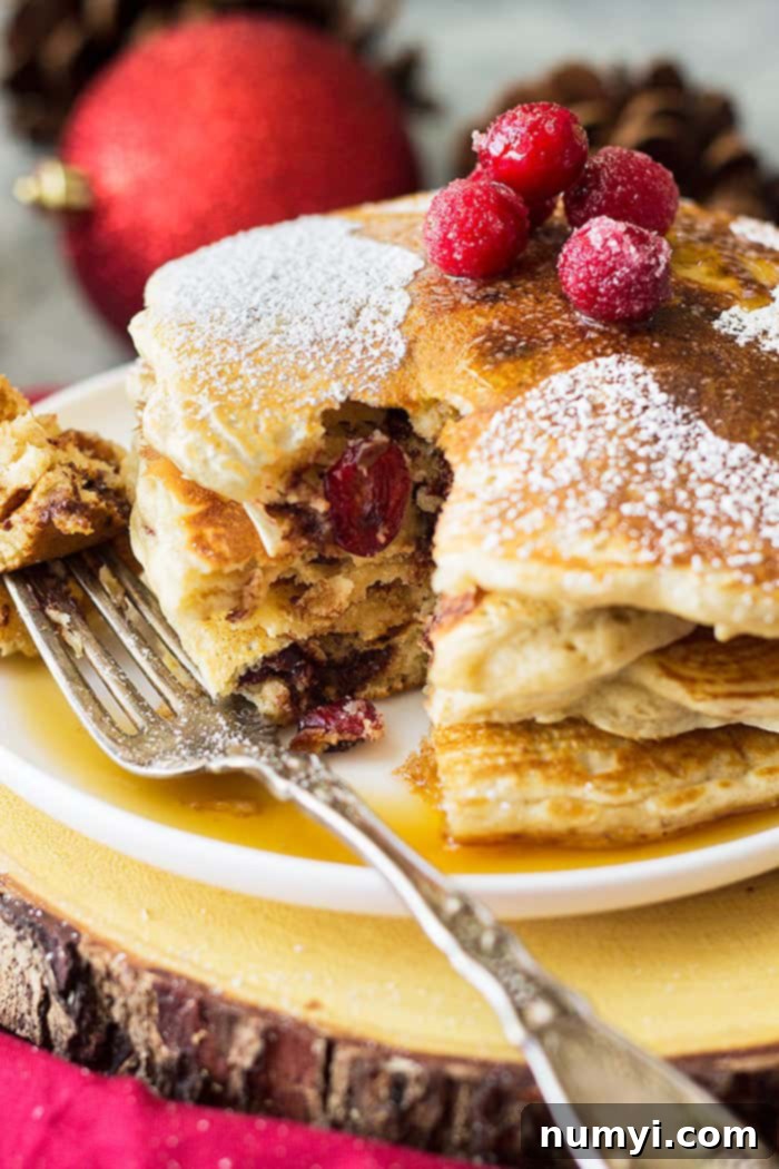 A bite taken from a stack of cranberry chocolate chip pancakes.
