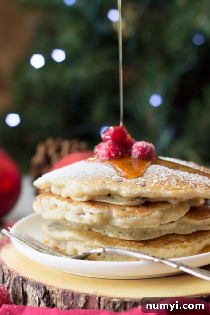 A stack of cranberry chocolate chip pancakes being drizzled with maple syrup.