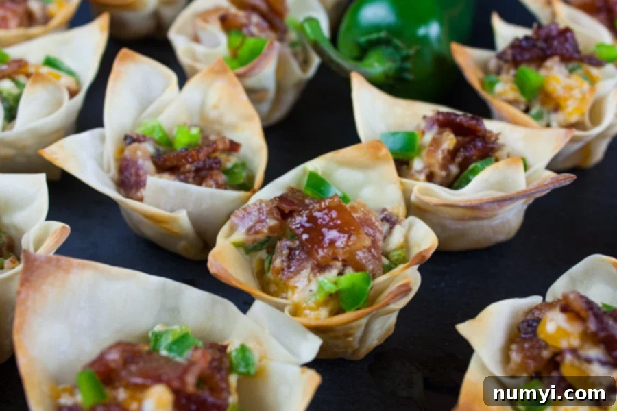 Candied Bacon Jalapeno Poppers lined up on a dark surface, showcasing their golden-brown wonton wrappers and glistening candied bacon topping.