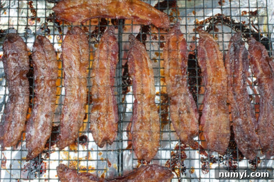 Crispy candied bacon cooling on a wire rack over a foil-lined baking sheet.