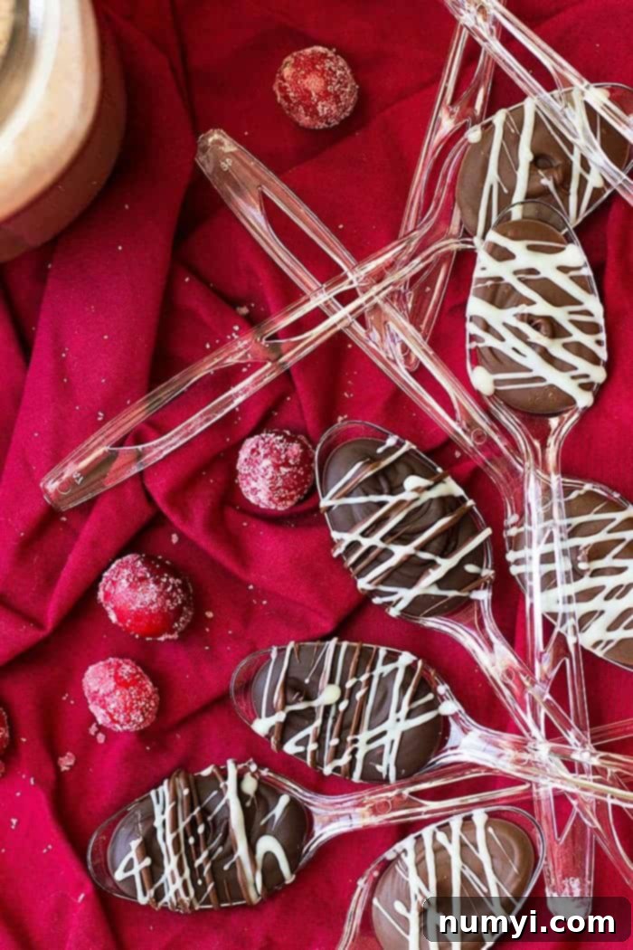 Several chocolate spoons with white chocolate drizzle on a red cloth, ready to be gifted.