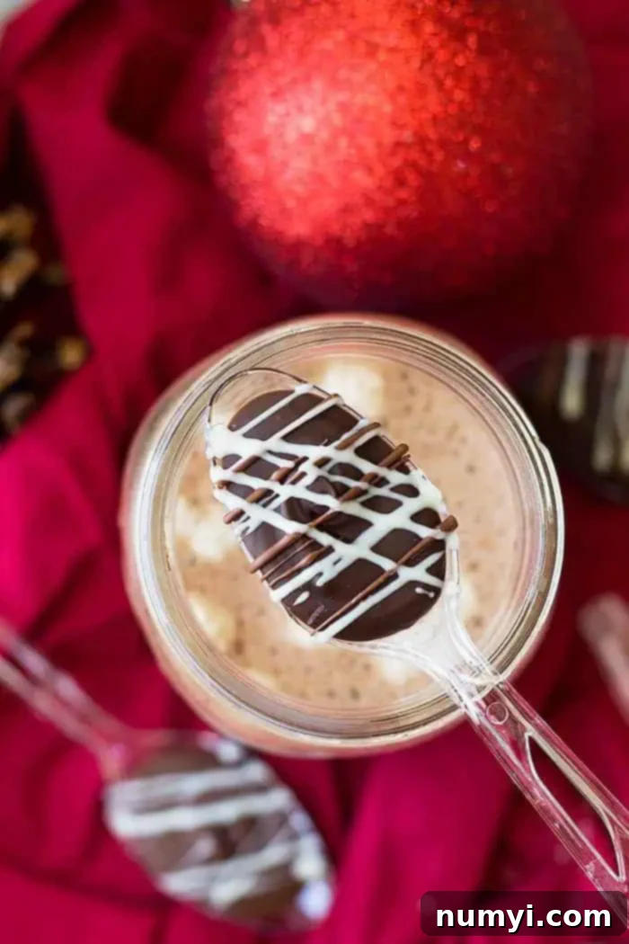 A chocolate spoon positioned over a steaming mug of hot cocoa, ready to be stirred in.