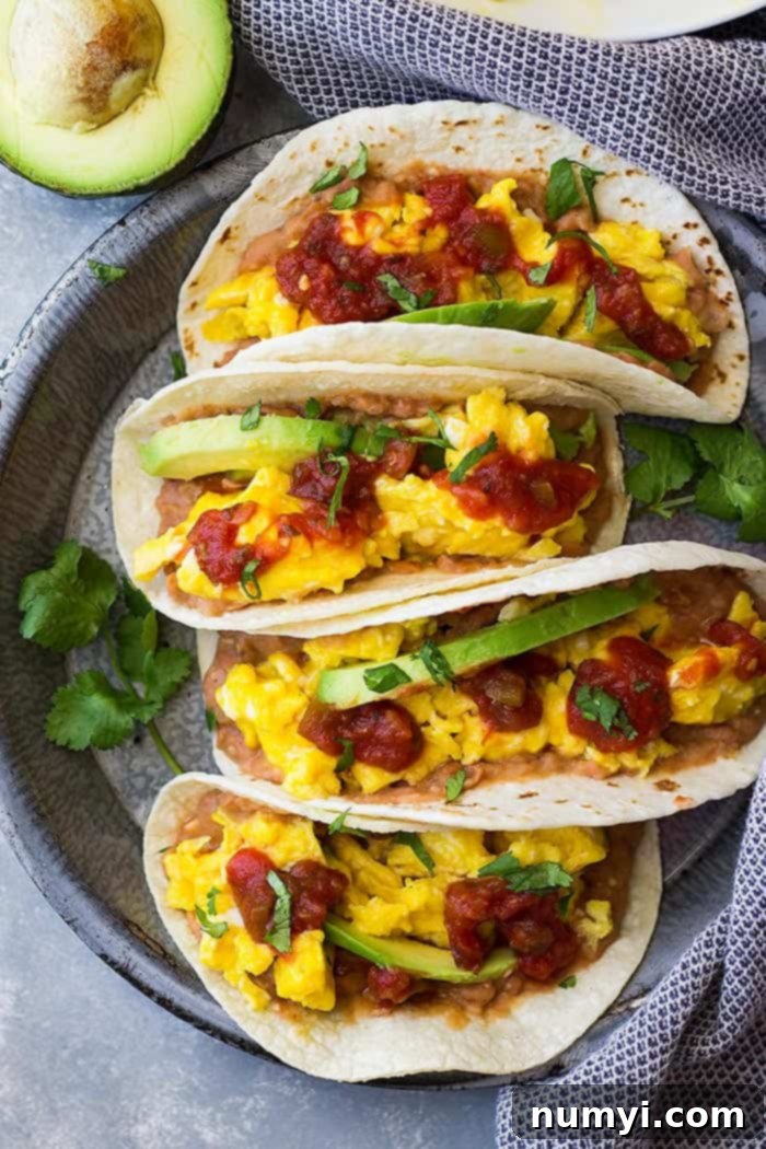 Sunrise Bean and Cheese Taco Bliss 2 Top down view of Bean and Cheese breakfast tacos topped with salsa and avocado slices.