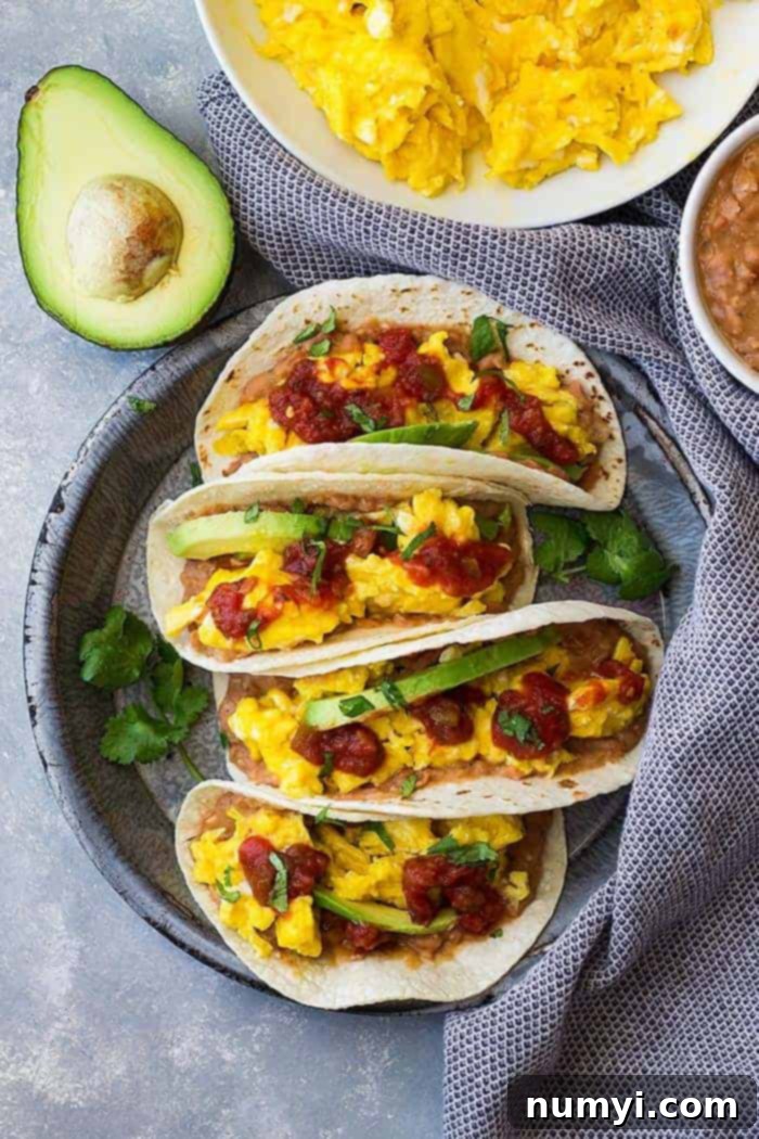 Sunrise Bean and Cheese Taco Bliss 5 Bean and cheese breakfast tacos topped with salsa and avocado with shredded cheddar off to the side.