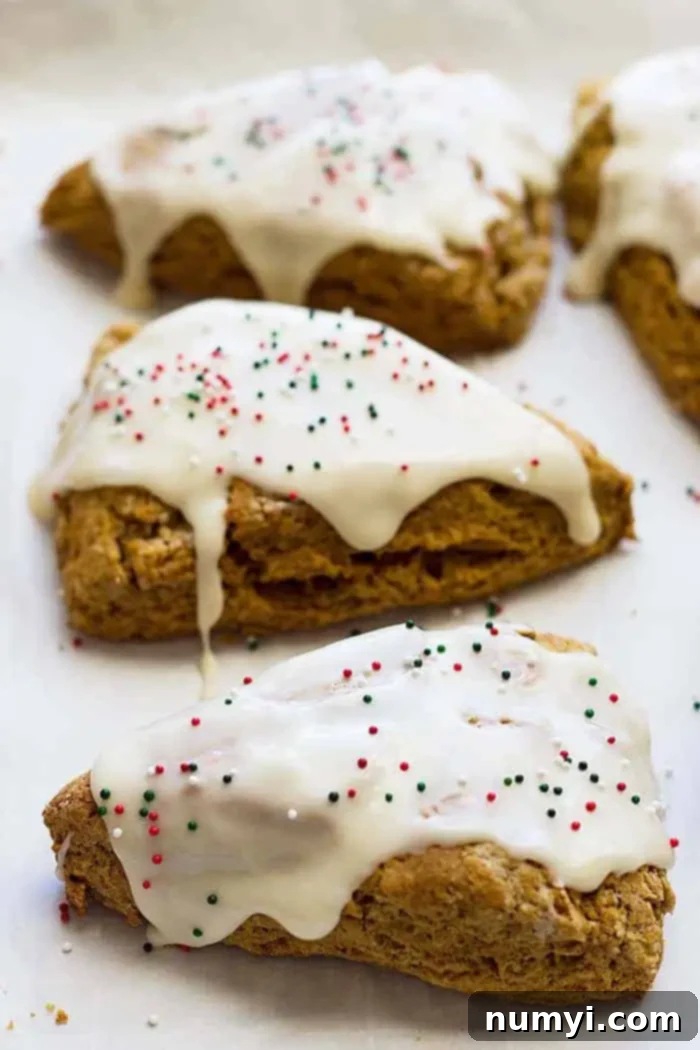 Warm Gingerbread Scones with Tangy Cream Cheese Frosting 2 Four gingerbread scones with cream cheese frosting and festive sprinkles on top, ready to be enjoyed.