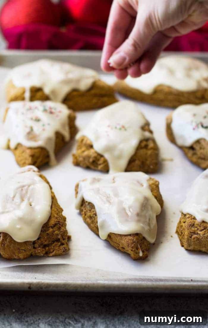 Warm Gingerbread Scones with Tangy Cream Cheese Frosting 3 Adding festive sprinkles on top of freshly frosted gingerbread scones, a simple scone recipe step.