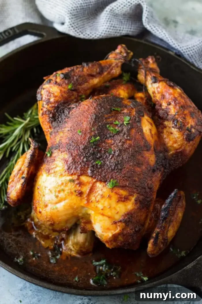 Baked rotisserie chicken in cast iron skillet with fresh herbs on top. 