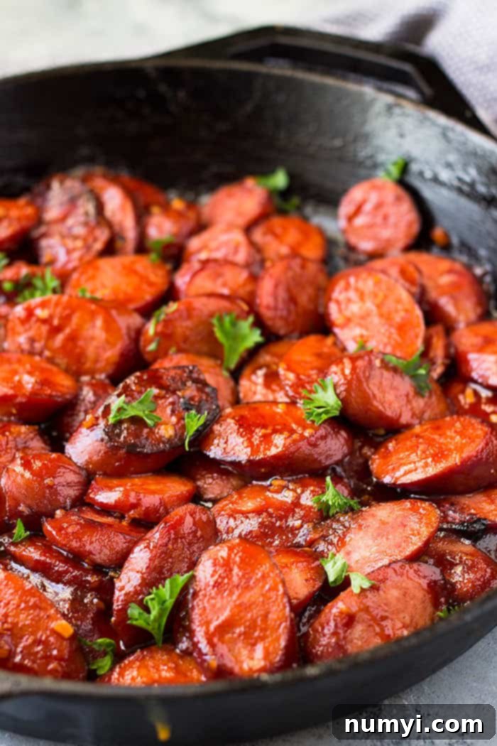 Smoked Sausage Skillet Delight 4 Close-up side view of succulent honey garlic smoked sausage glistening with a rich, sticky glaze in a hot skillet.