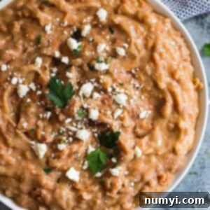 Overhead shot of a bowl of refried beans sprinkled with cheese.