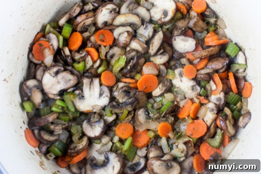 Diced celery, carrots, onion and sliced cremini mushrooms sautéing in a Dutch oven.