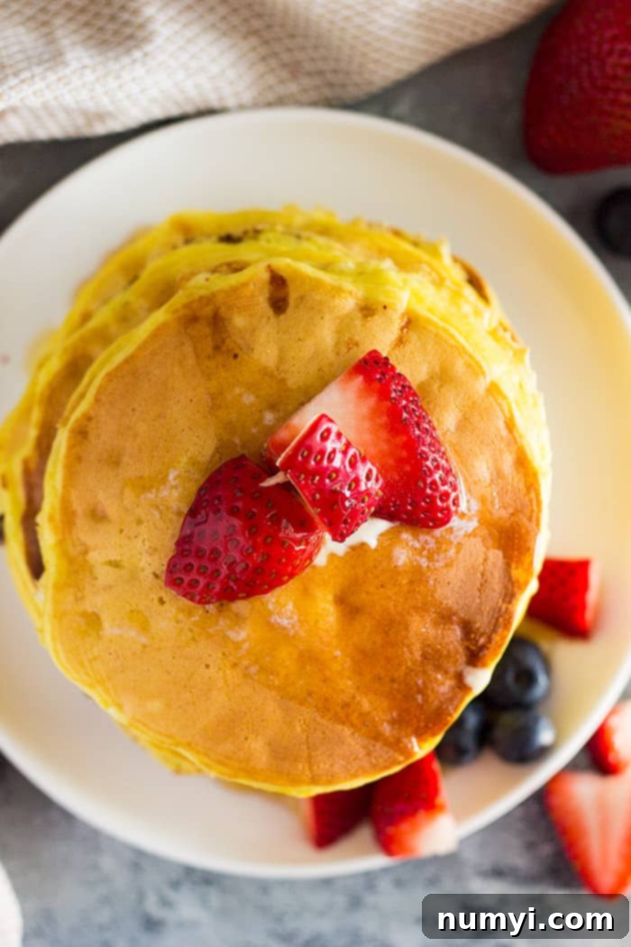 A top down view of a stack of high protein cottage cheese pancakes with fruit on top.