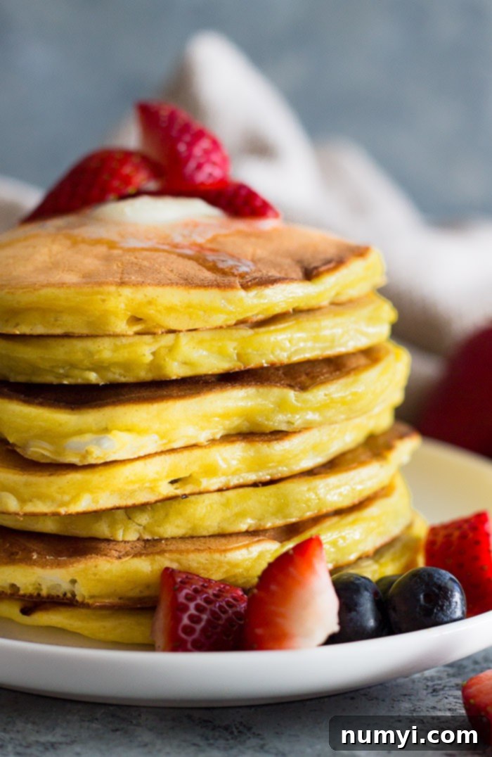Tall stack of high protein cottage cheese pancakes with melted butter and chopped fruit. 