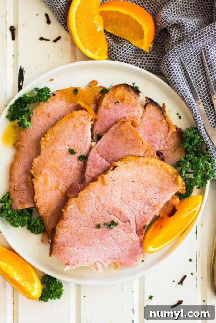 Irresistible Honey Mustard Ham Glaze 3 Slow cooker honey mustard glazed ham sliced and on a plate. Garnished with fresh parsley, ready to serve.