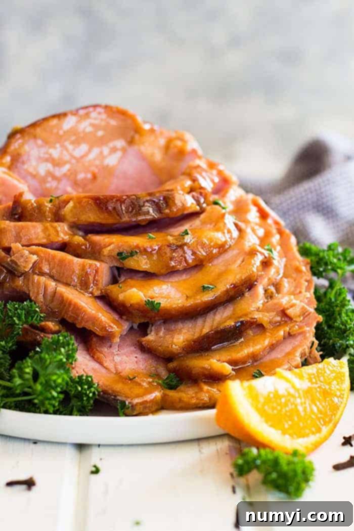 Irresistible Honey Mustard Ham Glaze 4 Slow cooker honey mustard glazed ham sliced and stacked tall on a plate. Garnished with chopped parsley, ready for a feast.