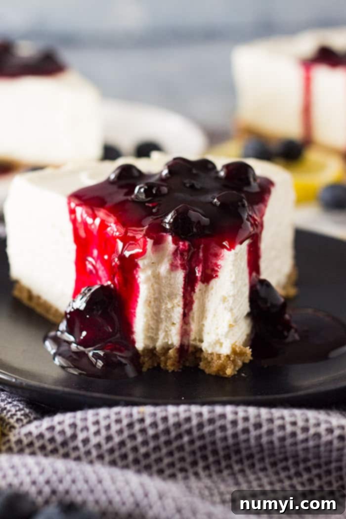 Slice of No Bake Lemon Blueberry Cheesecake with a bite taken out, showing creamy lemon filling and blueberry topping.
