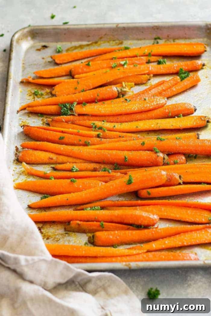 Honey garlic roasted carrots on a sheet pan garnished with fresh parsley, ready to serve.