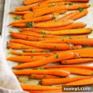 Honey garlic roasted carrots on a sheet pan garnished with parsley.