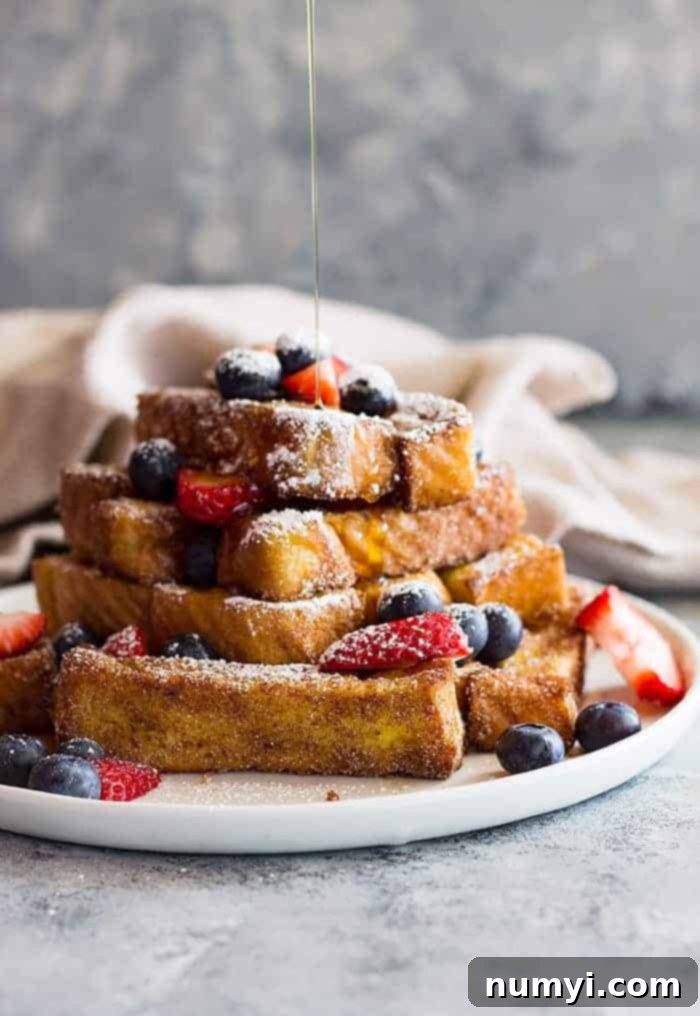 drizzling a stack of french toast sticks with syrup