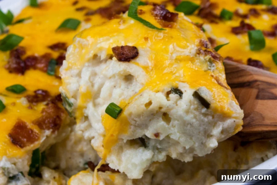 Loaded Cauliflower Mash Casserole with a serving being removed, showcasing its creamy texture and golden-brown toppings.